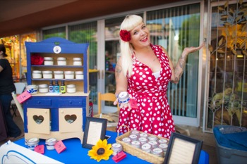 OCC alum jenna davis posing with her sunscreen product in a red and white polka dot dress