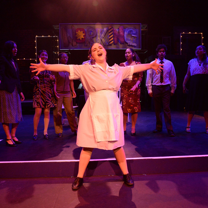 Woman singing with arms open wide.